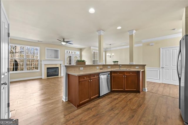 kitchen with light countertops, appliances with stainless steel finishes, brown cabinetry, open floor plan, and a sink