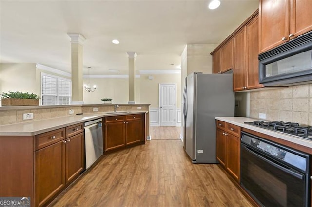 kitchen featuring pendant lighting, ornate columns, light countertops, brown cabinetry, and black appliances