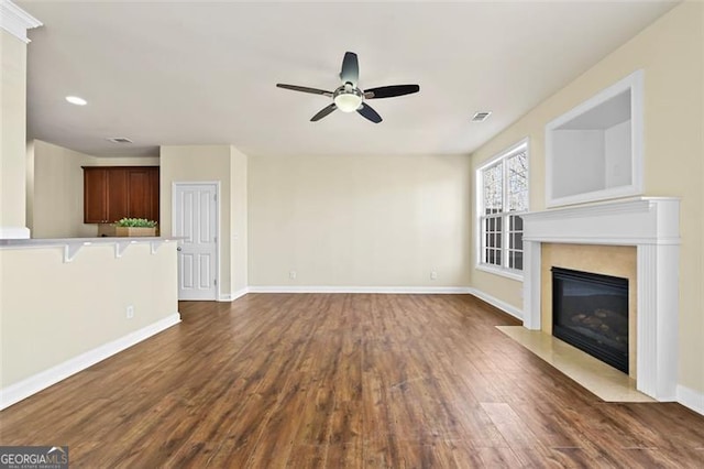 unfurnished living room featuring dark wood-style flooring, a fireplace, visible vents, a ceiling fan, and baseboards