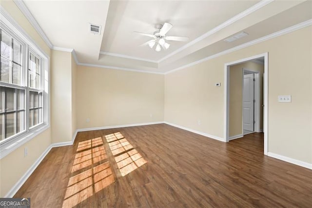 empty room featuring dark wood-type flooring, a raised ceiling, visible vents, and crown molding