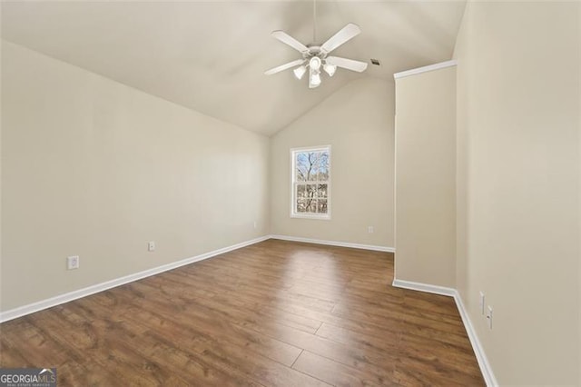 spare room featuring dark wood-style floors, lofted ceiling, ceiling fan, and baseboards