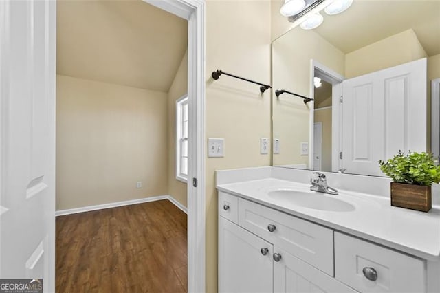 bathroom with vaulted ceiling, wood finished floors, vanity, and baseboards