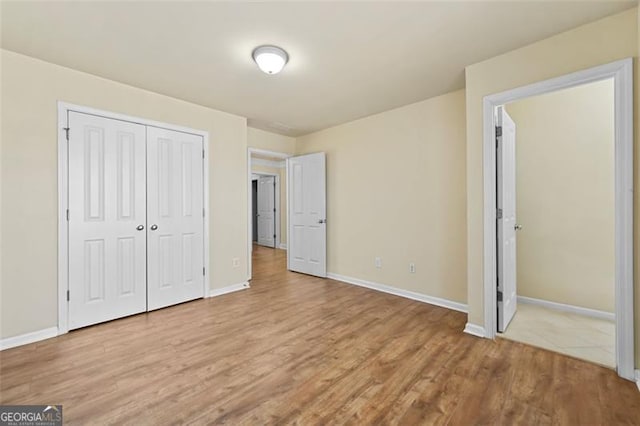 unfurnished bedroom with baseboards, a closet, and light wood-style floors