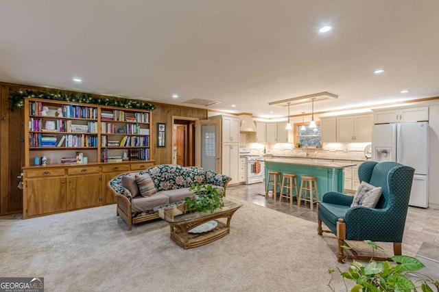 living area with wood walls, light colored carpet, crown molding, and recessed lighting