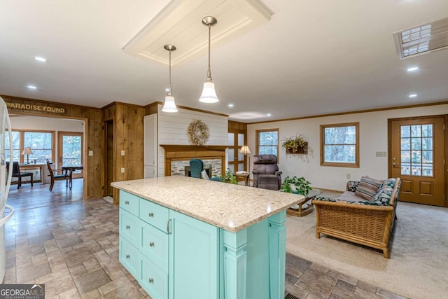 kitchen with open floor plan, ornamental molding, a center island, stone tile flooring, and pendant lighting