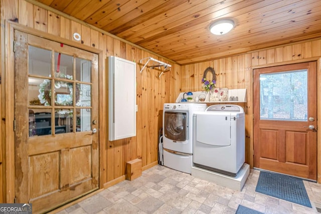 washroom featuring washing machine and clothes dryer, wooden ceiling, stone finish floor, wooden walls, and laundry area