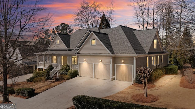 view of front facade featuring driveway, a shingled roof, a garage, and stairs