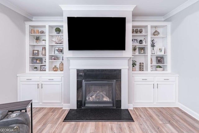 living room featuring light wood finished floors, ornamental molding, a fireplace with flush hearth, and baseboards