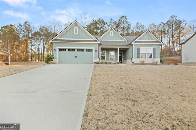 craftsman-style house with a garage, concrete driveway, roof with shingles, a front lawn, and board and batten siding