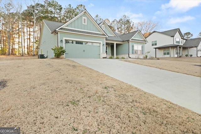 view of front of home featuring a garage, driveway, cooling unit, board and batten siding, and a front yard