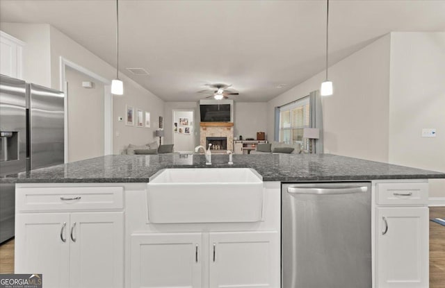 kitchen featuring a large fireplace, visible vents, appliances with stainless steel finishes, open floor plan, and a sink