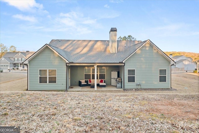 rear view of property with a chimney, a patio, and an outdoor living space