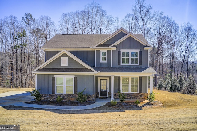 craftsman-style house with stone siding, a shingled roof, and board and batten siding