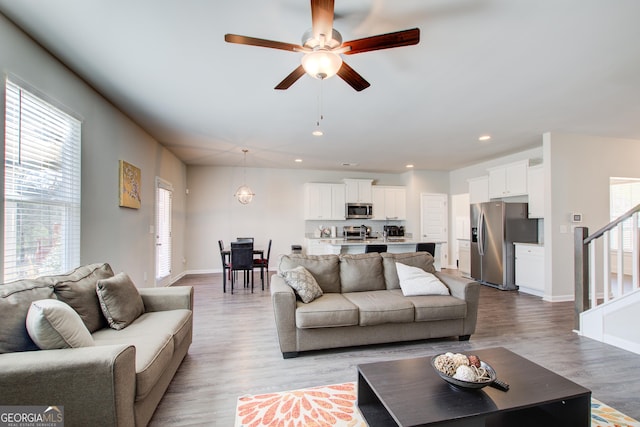 living room with light wood finished floors, recessed lighting, stairway, a ceiling fan, and baseboards