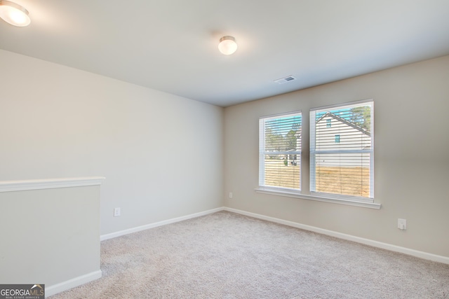 spare room with baseboards, visible vents, and light colored carpet