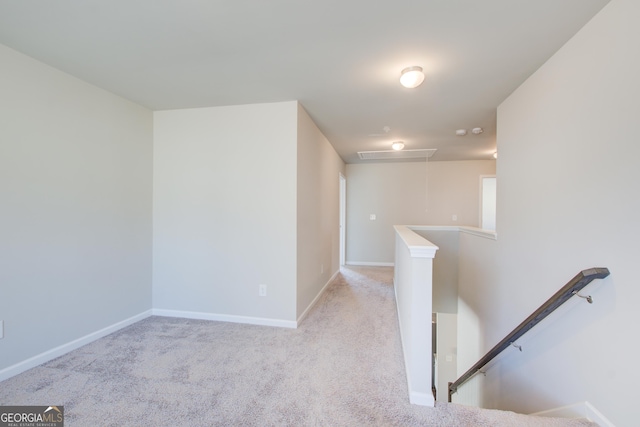 corridor featuring attic access, baseboards, light carpet, and an upstairs landing