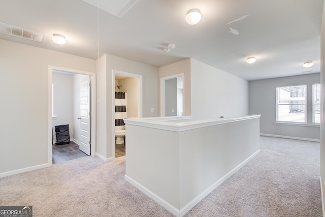 hall with attic access, baseboards, visible vents, carpet flooring, and an upstairs landing