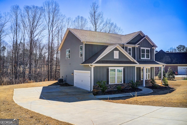 craftsman-style home featuring central AC unit, concrete driveway, stone siding, roof with shingles, and board and batten siding