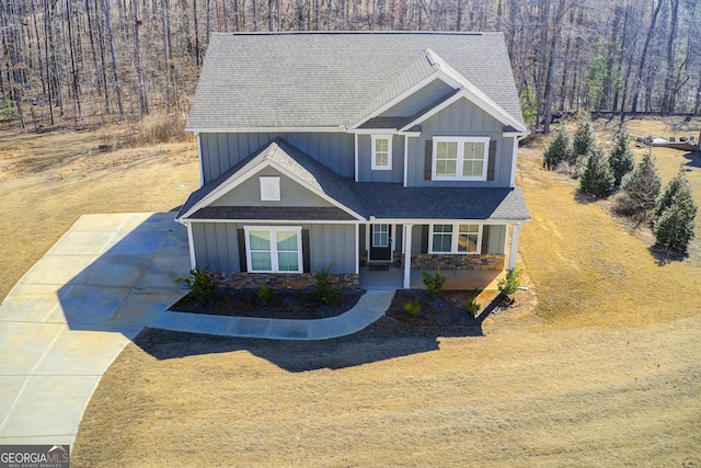 craftsman house with a shingled roof, concrete driveway, covered porch, board and batten siding, and stone siding