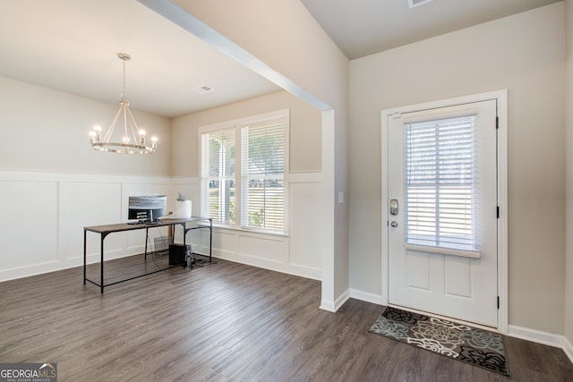 entryway featuring an inviting chandelier, visible vents, a decorative wall, and dark wood-type flooring