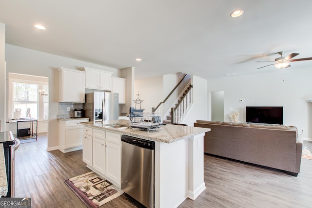 kitchen with appliances with stainless steel finishes, a kitchen island with sink, and white cabinets