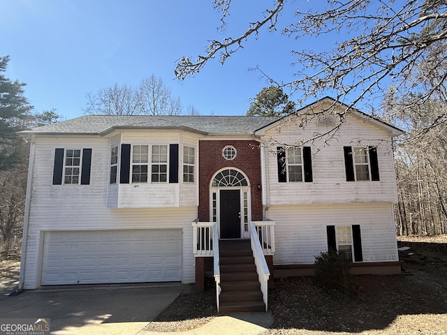 split foyer home featuring driveway, a garage, and brick siding