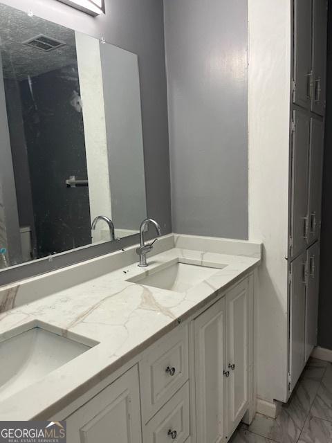 bathroom with a sink, double vanity, and marble finish floor
