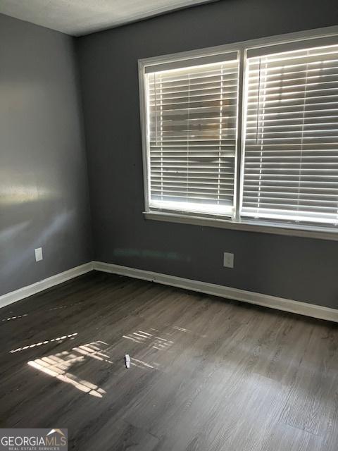 spare room featuring baseboards and wood finished floors