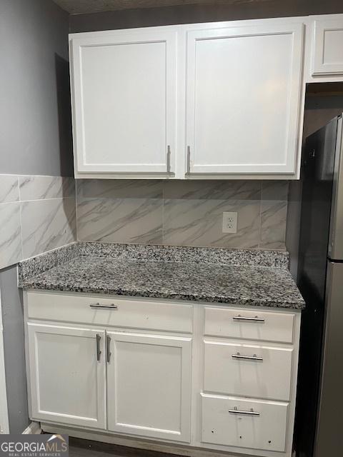 3235 Wintercreeper Dr, Lithonia, GA 30038 - kitchen featuring freestanding refrigerator, white cabinetry, and dark stone counters