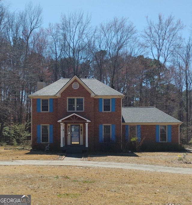 view of front of property featuring brick siding and a chimney