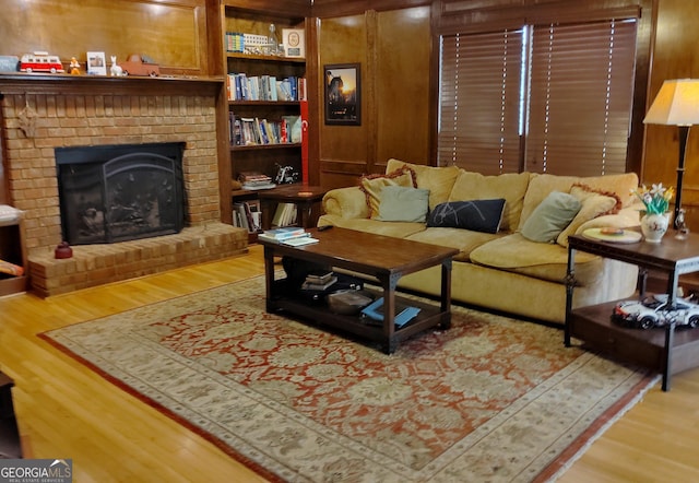 living room with a brick fireplace and wood finished floors