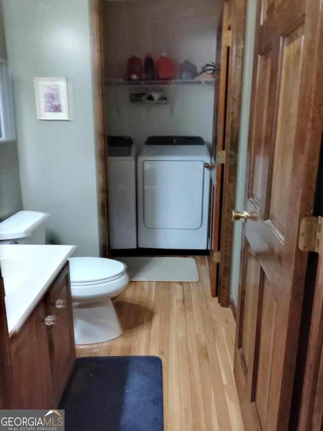 bathroom featuring toilet, wood finished floors, vanity, and washer and dryer