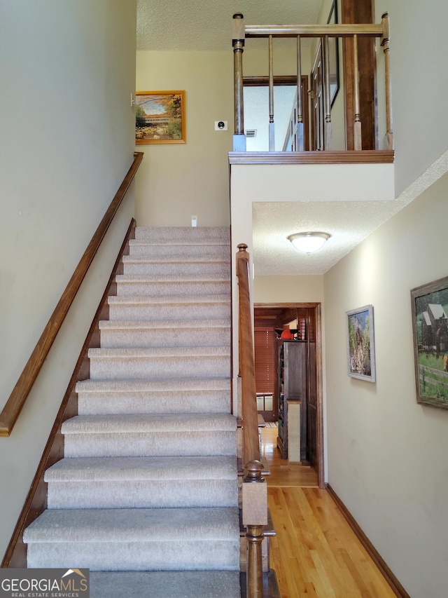 stairs with baseboards, a textured ceiling, and wood finished floors