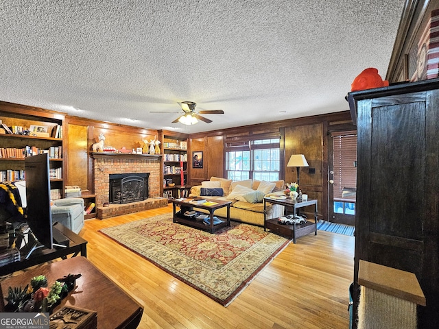 230 Mapledale Trl, Sharpsburg, GA 30277 - living room featuring a ceiling fan, wooden walls, light wood-type flooring, a textured ceiling, and a brick fireplace