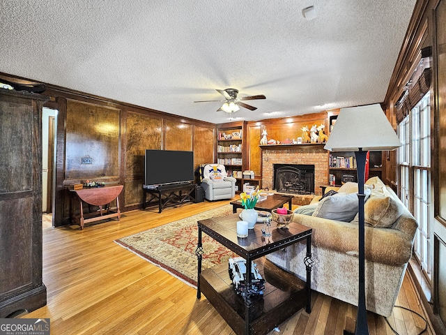 230 Mapledale Trl, Sharpsburg, GA 30277 - living room featuring ceiling fan, light wood finished floors, a textured ceiling, a fireplace, and wood walls