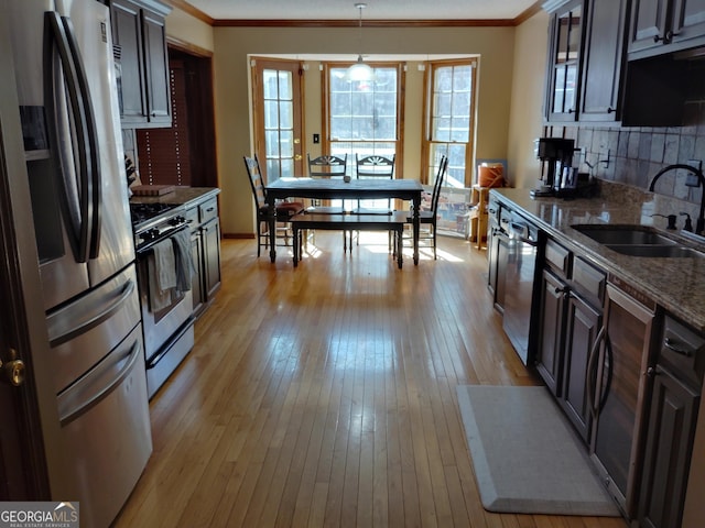 kitchen with stainless steel appliances, dark brown cabinets, a sink, and pendant lighting