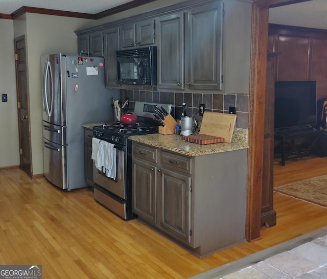 kitchen with light wood finished floors, appliances with stainless steel finishes, light stone counters, ornamental molding, and backsplash