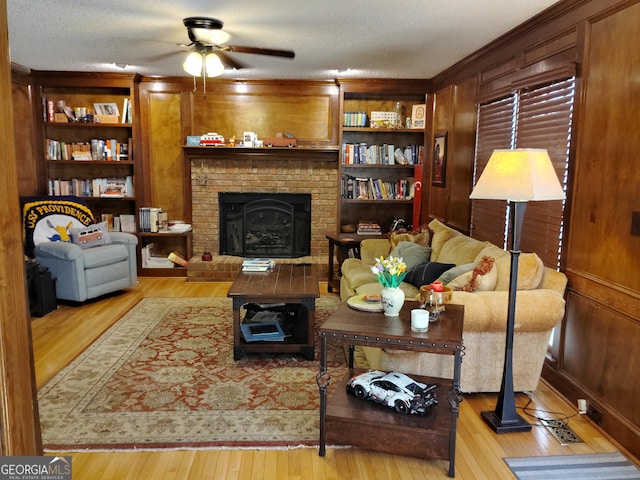 living room featuring light wood-style floors, ceiling fan, wooden walls, and built in features