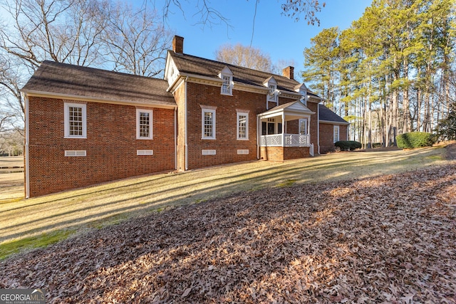 view of home's exterior featuring crawl space, a chimney, a lawn, and brick siding