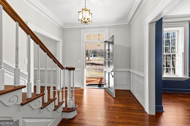 foyer with stairs, dark wood-type flooring, a chandelier, and crown molding