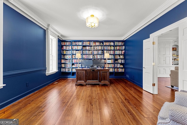 unfurnished office featuring built in shelves, ornamental molding, and dark wood finished floors