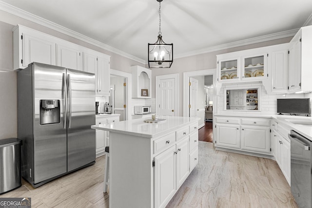 kitchen featuring stainless steel appliances, light countertops, a kitchen island, and white cabinetry