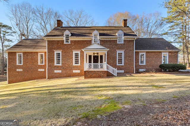 back of house with crawl space, brick siding, a lawn, and a chimney