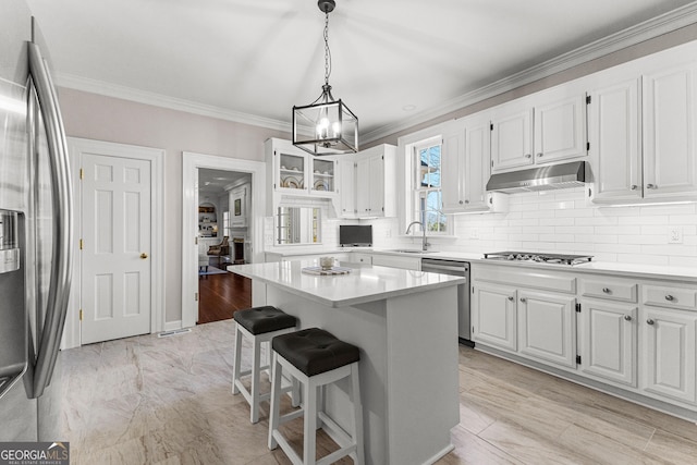 kitchen with under cabinet range hood, a kitchen island, white cabinetry, light countertops, and appliances with stainless steel finishes