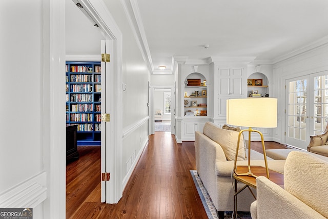 sitting room featuring a healthy amount of sunlight, built in features, dark wood-style flooring, and french doors
