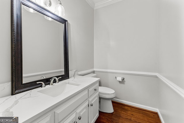 bathroom with baseboards, toilet, ornamental molding, wood finished floors, and vanity