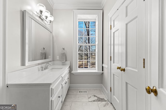 bathroom featuring marble finish floor, ornamental molding, vanity, and a healthy amount of sunlight