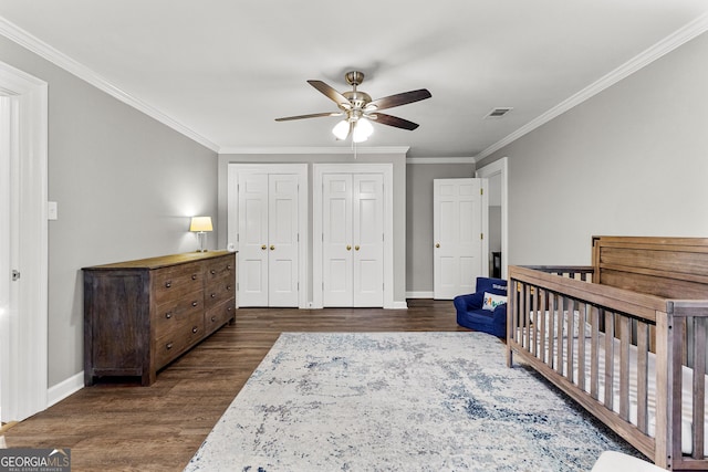 bedroom featuring dark wood-style floors, baseboards, visible vents, and crown molding