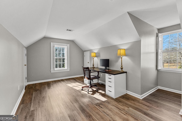 unfurnished office featuring lofted ceiling, baseboards, visible vents, and wood finished floors