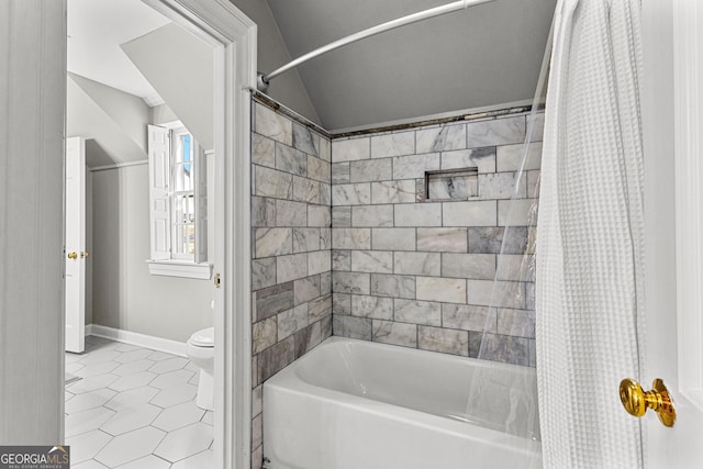 full bath featuring toilet, baseboards, vaulted ceiling, tile patterned floors, and shower / bath combo
